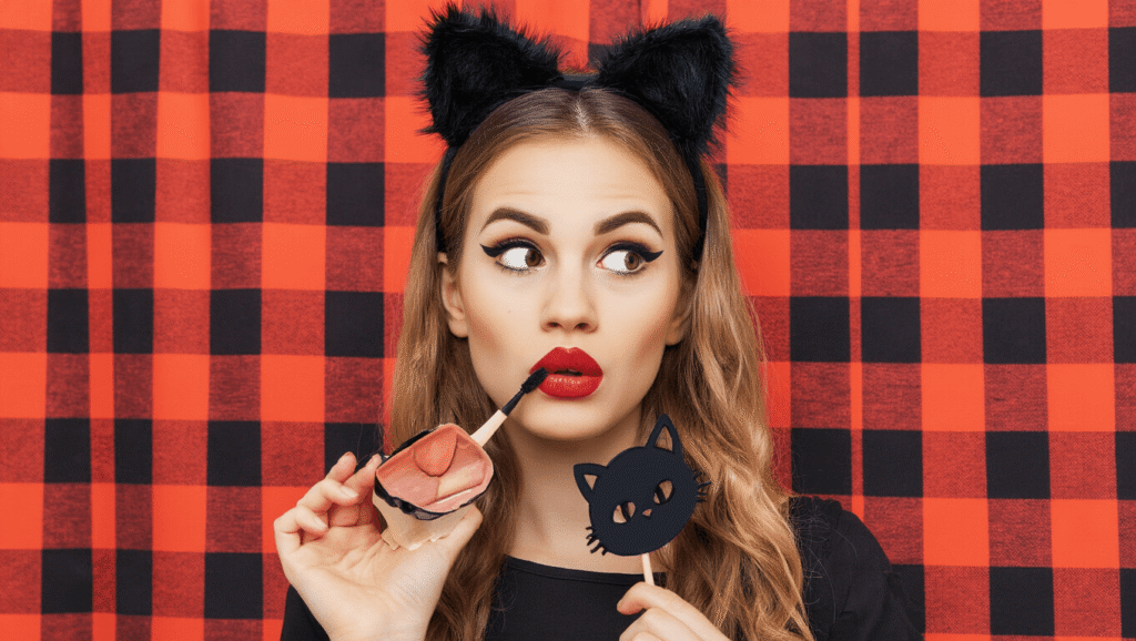 A Halloween costume featuring a black dress, cat ears, and dramatic makeup against a clean background.