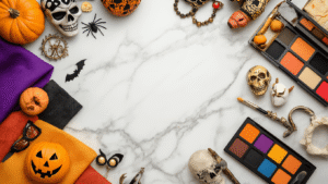 A flat lay of couples Halloween costumes featuring colorful fabric swatches, vintage accessories, makeup palettes, character props, and DIY crafting materials arranged on a white marble surface, illuminated by soft golden hour lighting.