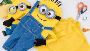 A minion costume made from yellow fabric, featuring blue overalls and black goggles, surrounded by crafting supplies on a clean background.