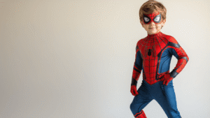 A young boy in a vibrant Spider-Man costume with detailed web textures and muscle padding, posed confidently on a clean white background during golden hour, highlighting the costume's craftsmanship and the child's excitement in a cozy Halloween atmosphere.